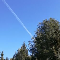 Low angle view of vapor trail against clear blue sky