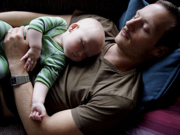 Father and son sleeping on sofa at home