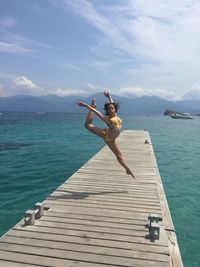 Portrait of teenage girl dancing on pier over sea