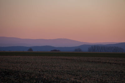 Scenic view of agricultural field against sky during sunset