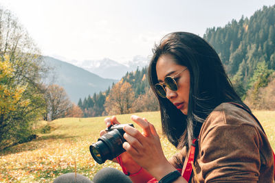 Woman photographing against mountains
