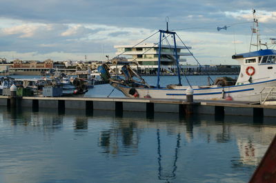 Boats moored at harbor against sky