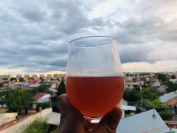 Close-up of hand holding drink against sky