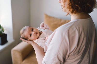 Portrait of happy mum holding infant child on hands.