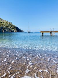 Sailboats in sea against clear blue sky