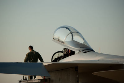 Rear view of man sitting on airplane against clear sky