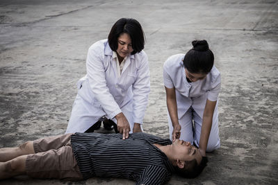 Nurse and doctor examining man lying outdoors