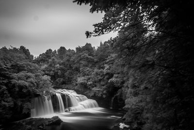 Scenic view of waterfall against trees