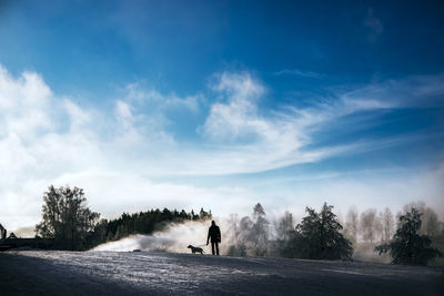 Silhouette person on field against sky during winter