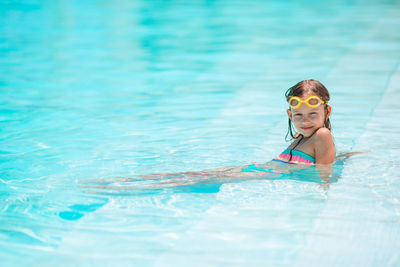 Portrait of cute girl sitting at swimming pool