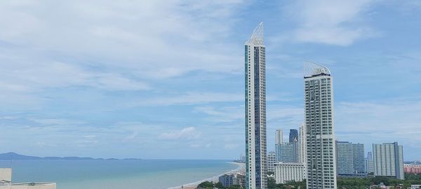 Modern buildings by sea against sky