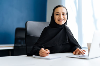 Portrait of businesswoman using laptop at office