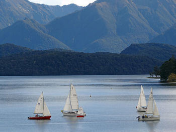 Sailboats in sea against mountains
