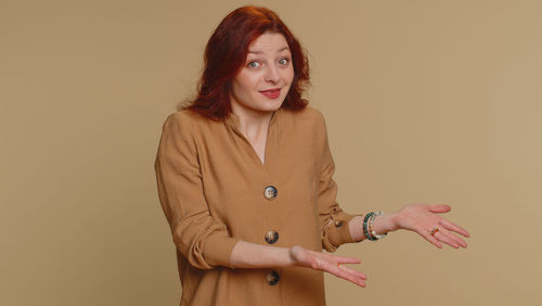 Portrait of young woman standing against pink background