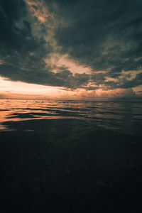 Scenic view of sea against dramatic sky during sunset