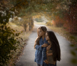 Sisters with a family album in their hands stand in the fall in nature