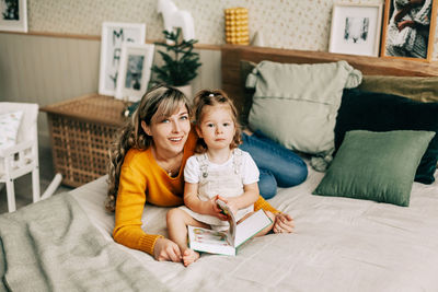 Mom and daughter read fairy tales in the bedroom on the bed on christmas or new year's eve.