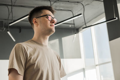 Side view of young man looking through window