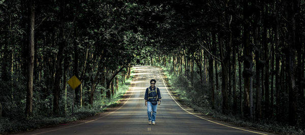 Rear view of man walking on road in forest