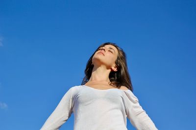 Low angle view of woman looking at blue sky