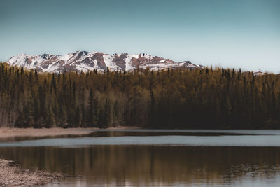 Scenic view of lake by snowcapped mountain against sky