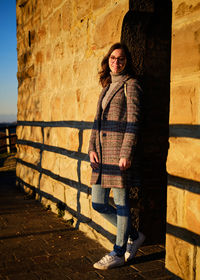 Rear view of young woman standing against wall