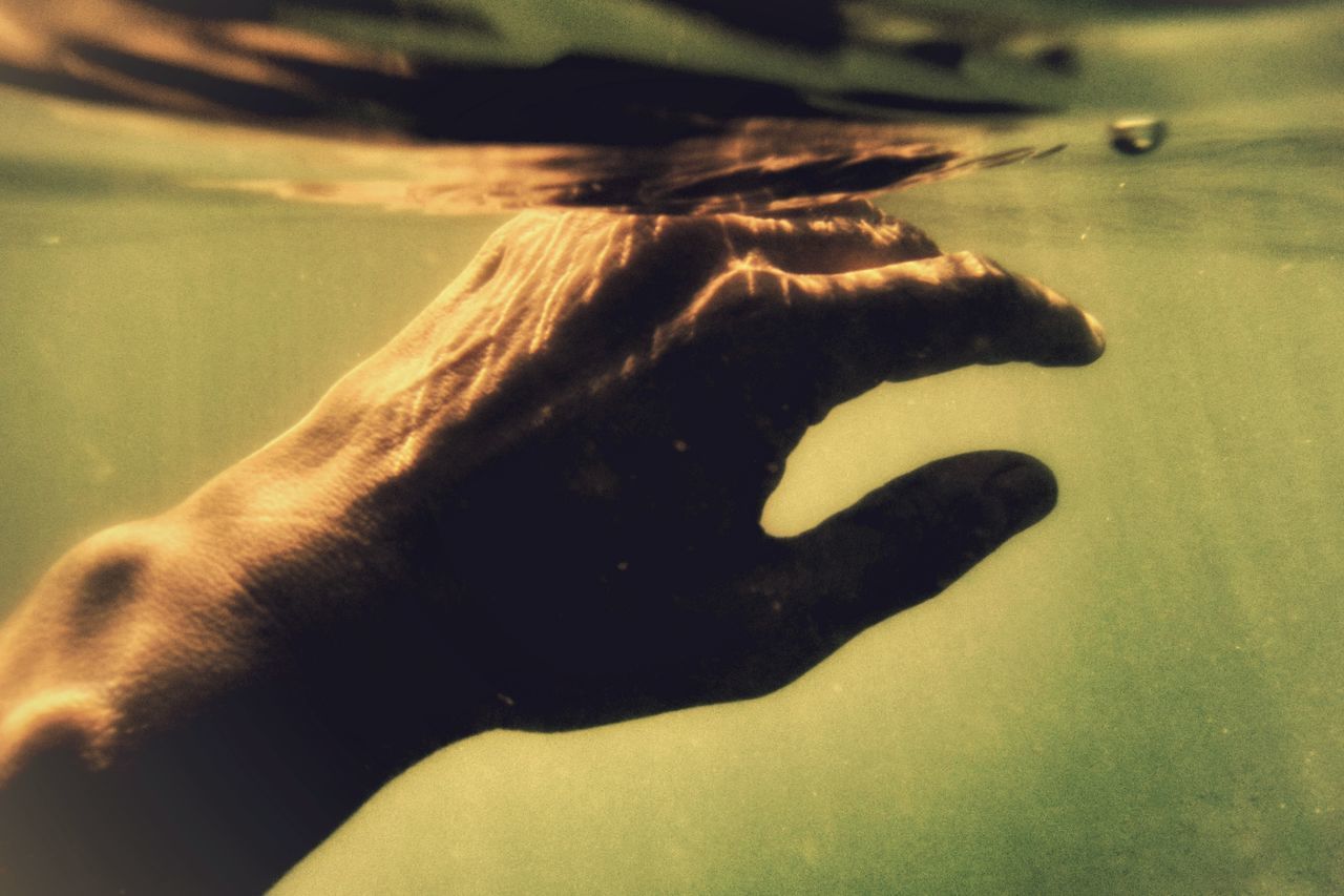 CLOSE-UP OF HAND TOUCHING SEA