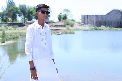 Portrait of young man standing by lake