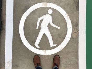 Low section of person standing on road sign