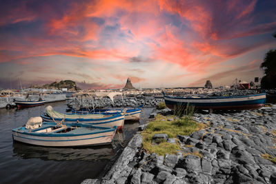 Boats moored on beach against sky during sunset