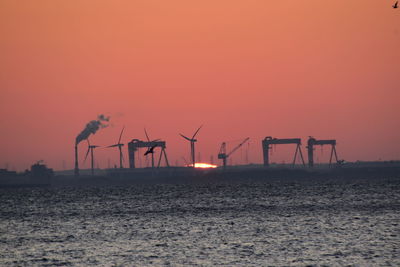 Silhouette people on shore against clear sky during sunset