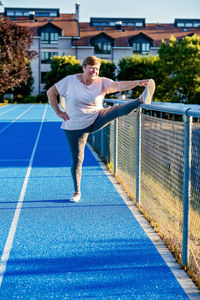 Full length of young woman exercising on court