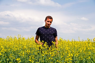 Man standing on oilseed rape field against sky