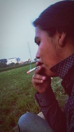 Close-up of man smoking cigarette against sky