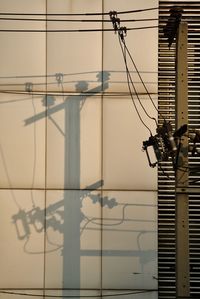 Low angle view of telephone pole against wall