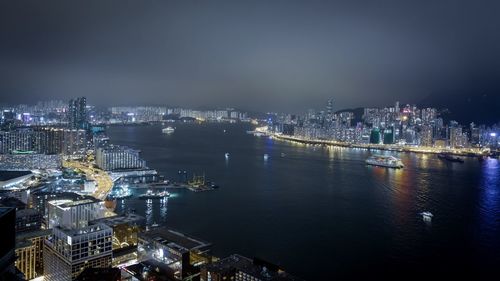 Illuminated city by river at night