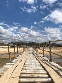 View of empty footpath leading towards sky