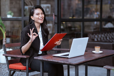 Young woman using laptop at cafe