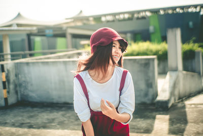 Young woman smiling while standing against built structure