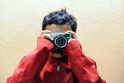 Boy photographing while standing against wall