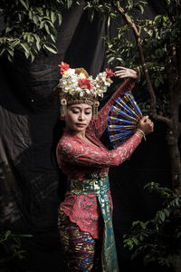 Woman wearing traditional clothing while dancing against backdrop