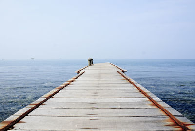 Pier over calm sea against clear sky