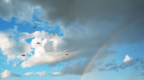 Flying kites in a sky with clouds and a rainbow