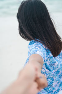 Side view of woman holding person hand at beach