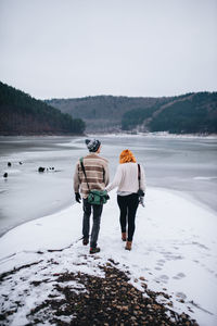 Rear view of people walking on snow covered mountain