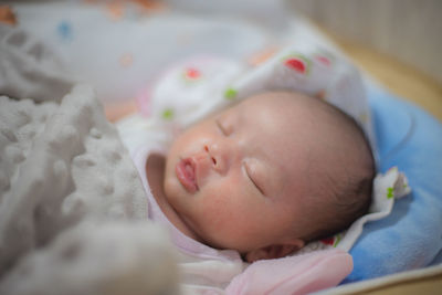 Close-up of cute baby boy lying on bed at home