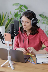 Portrait of woman using mobile phone while sitting on table