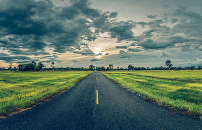 Road amidst field against sky