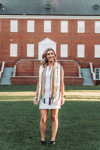 Full length of a smiling young woman standing against building