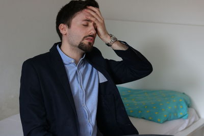 Young man holding camera against wall